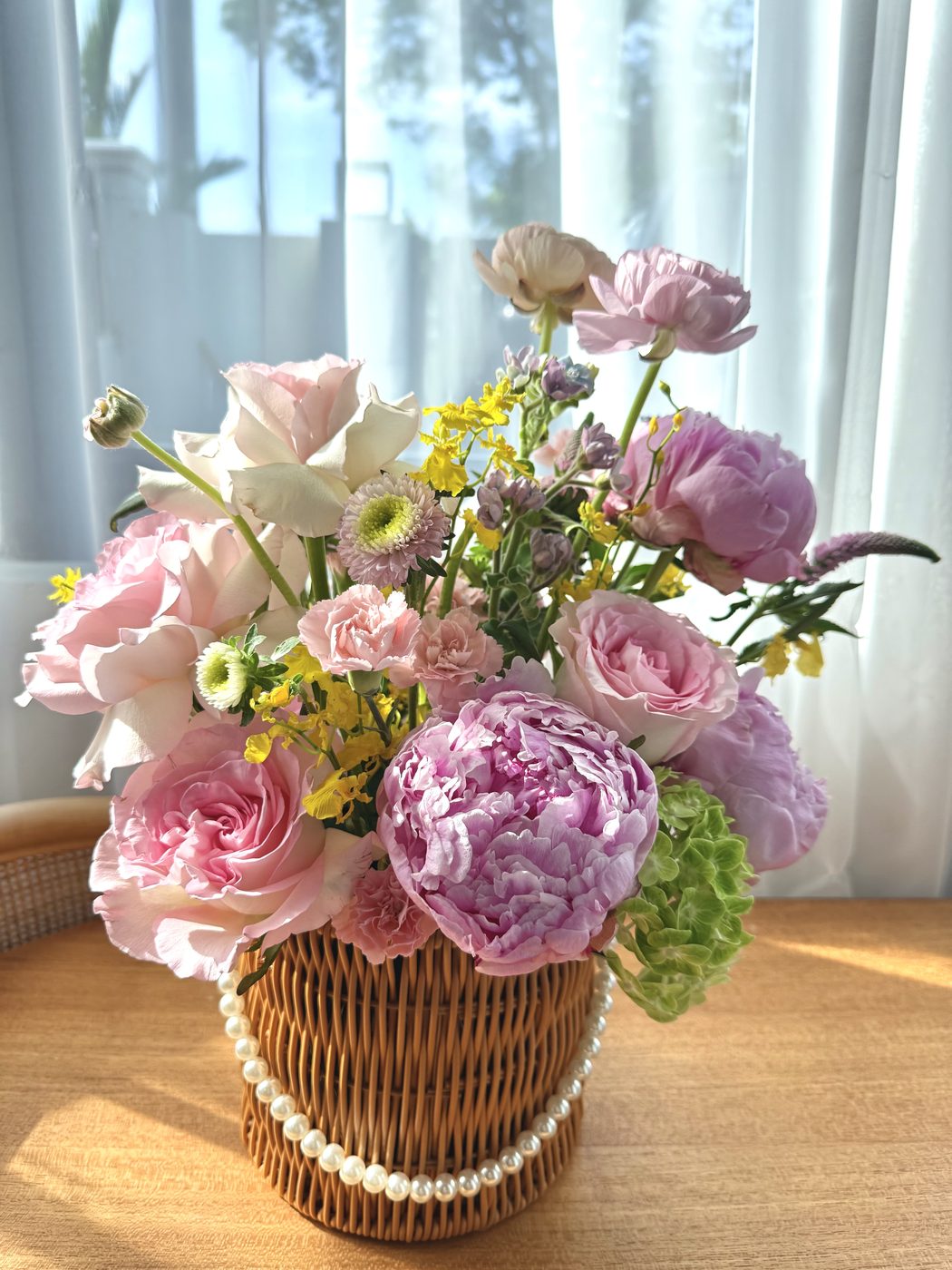 Fleurtatious floral arrangement in a woven basket with pearl trim